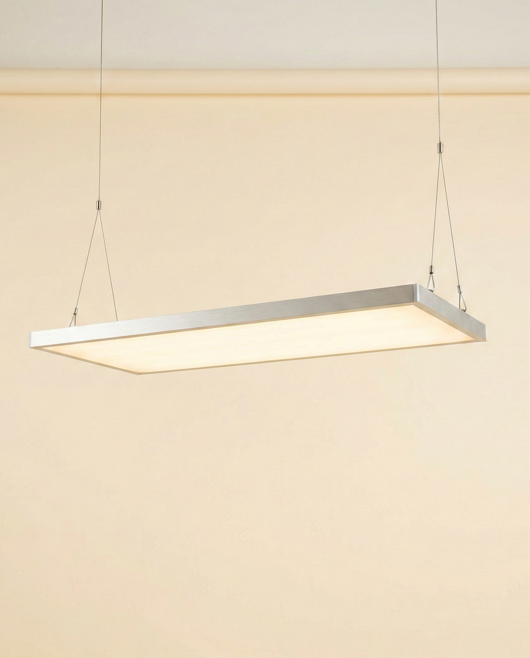 A modern, ultra-thin full-spectrum LED grow light panel suspended by thin wire cables, emitting a warm glow.